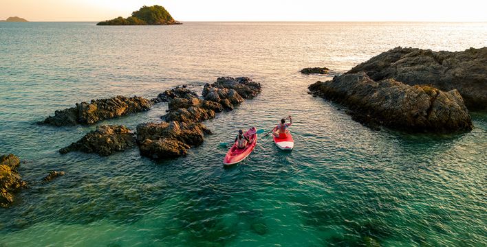 Frau in einem Kanu und Frau auf einem Stand up Paddle unterwegs auf dem Meer