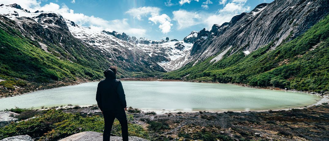 Reisender blickt auf einen türkisfarbenen Bergsee bei Ushuaia in Patagonien