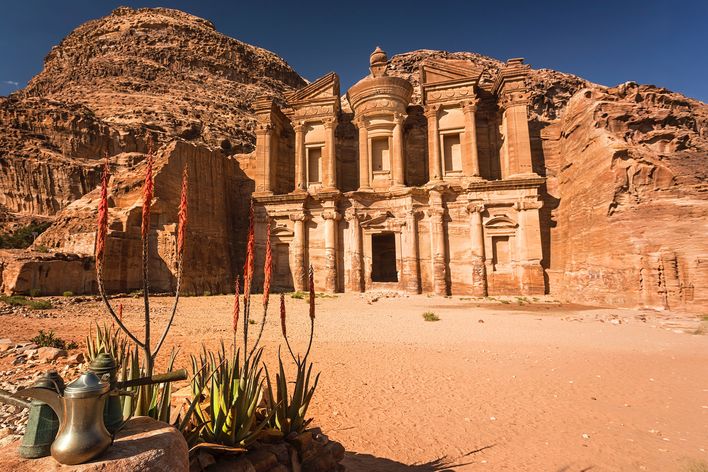 Die in den Fels geschlagene Felsenstadt Petra mit Wüstenblumen im Vordergrund, Jordanien