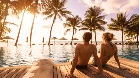 Paar sitzt am Pool und genießt die Sonne