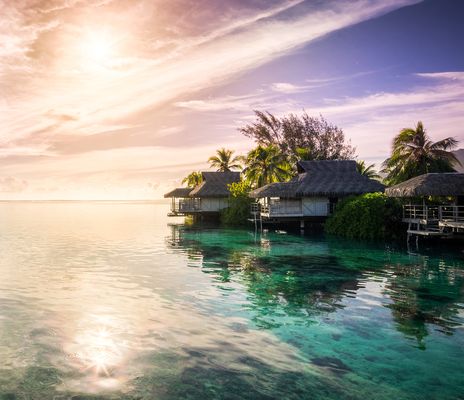 Überwasser-Villen an einer tropischen Lagune im Abendlicht