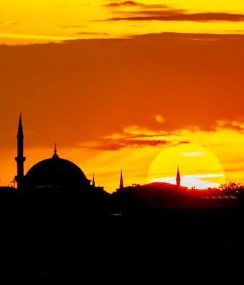 Sonnenuntergang über Istanbul mit Silhouette von Minaretten und Kuppeln vor orangefarbenem Himmel.