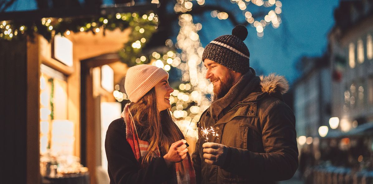 Paar mit Wunderkerzen am Weihnachtsmarkt