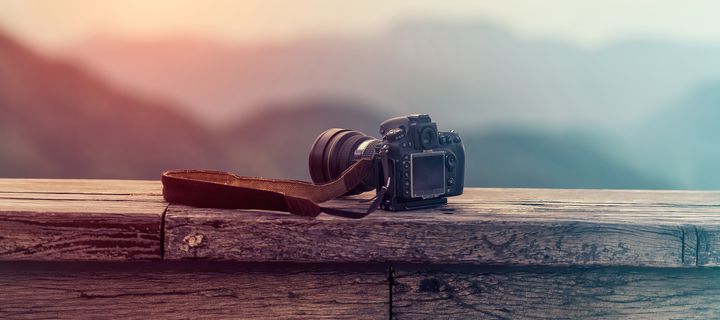 Eine Spiegelreflexkamera liegt auf einer Mauer 