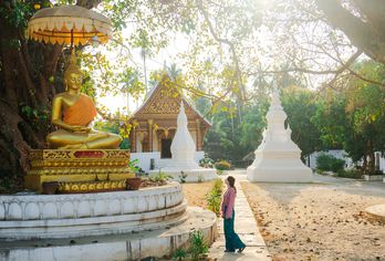 Frau steht vor einer Buddha Statue in Luang Prabang, Laos