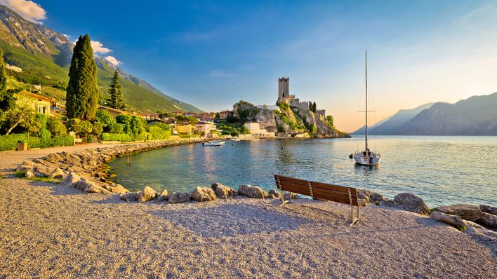 Strand in Malcesine am Gardasee mit Blick auf die Scaligerburg und Segelboot bei Sonnenuntergang