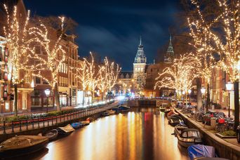 Weihnachtlicht geschmückte Bäume entlang der Grachten in Amsterdam
