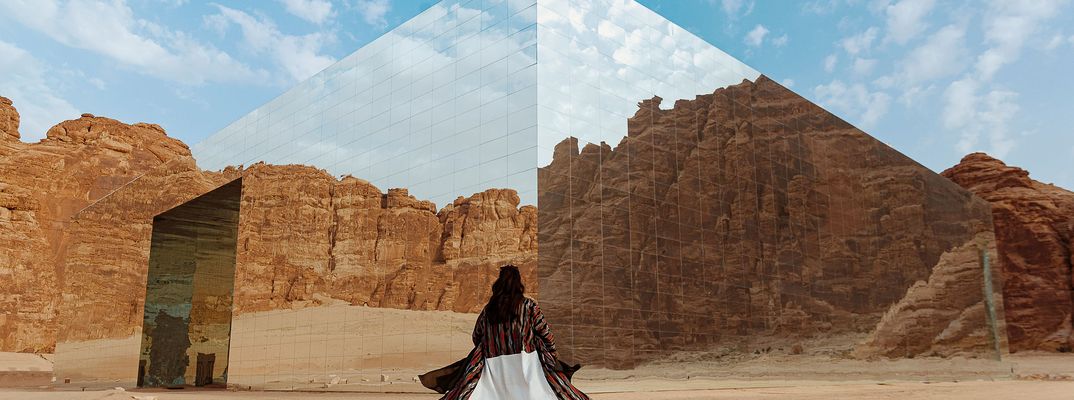 Frau in traditioneller Kleidung in der Wüste von Al-Ula zwischen Felsformationen