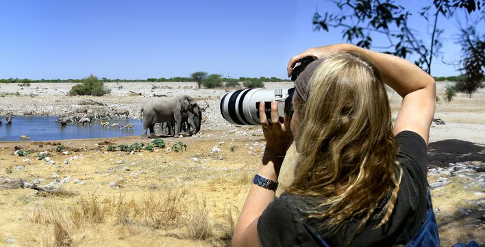 Reisende fotografiert Wildtiere am Wasserloch im Etosha-Nationalpark in Namibia