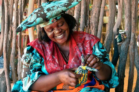 Frau in traditioneller Kleidung in Namibia mit Handwerk