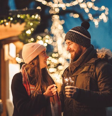 Paar mit Wunderkerzen am Weihnachtsmarkt