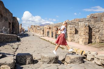 Frau balanciert über Steine im archäologischen Park Pompeji in Kampanien am Golf von Neapel