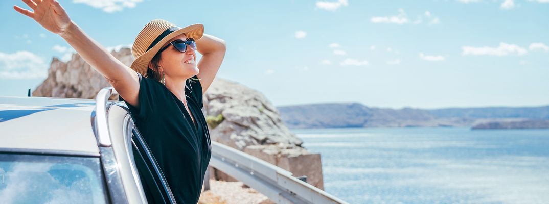 Frau blickt aus dem Auto aufs Meer