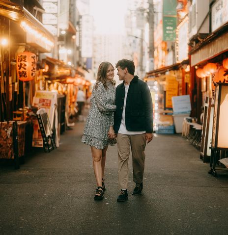 Fröhliches junges Paar, das durch eine Gasse in Tokio läuft