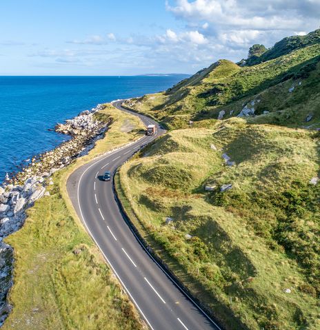 Mietwagen fährt auf einer Straße an der Küste von Irland