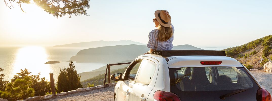 Frau blickt auf aus ihrem Auto auf eine Landschaft am Meer