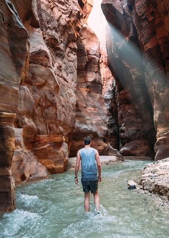 Ein Mann watet durch den Bachlauf in der Schlucht von Wadi Mujib in Jordanien