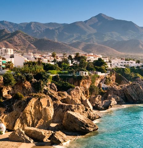 Felsige Buchten und weiße Häuser prägen die sonnige Mittelmeerküste von Nerja vor den Bergen Andalusiens.