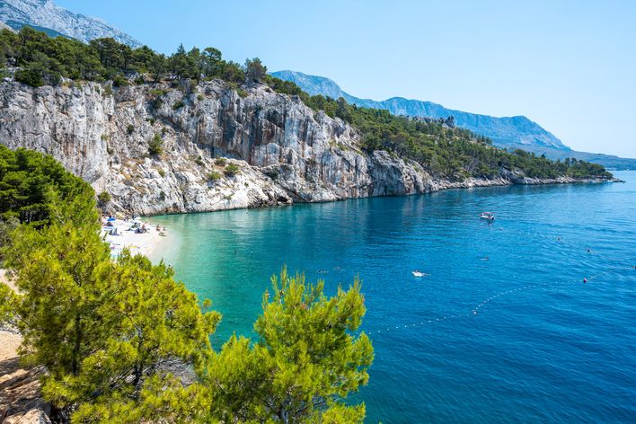Blick auf den abgeschiedenen Nugal Beach an der Makarska Riviera in Kroatien, gesäumt von Pinien und Felsen