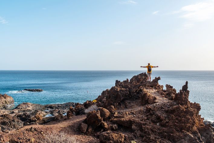 Mann beim Wandern auf der Insel El Hierro auf einem Felsweg mit Ausblick auf das Meer