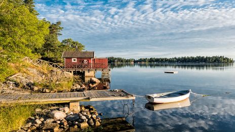 Ein See mit einer skandinavischen Hütte und einem Steeg in Schweden