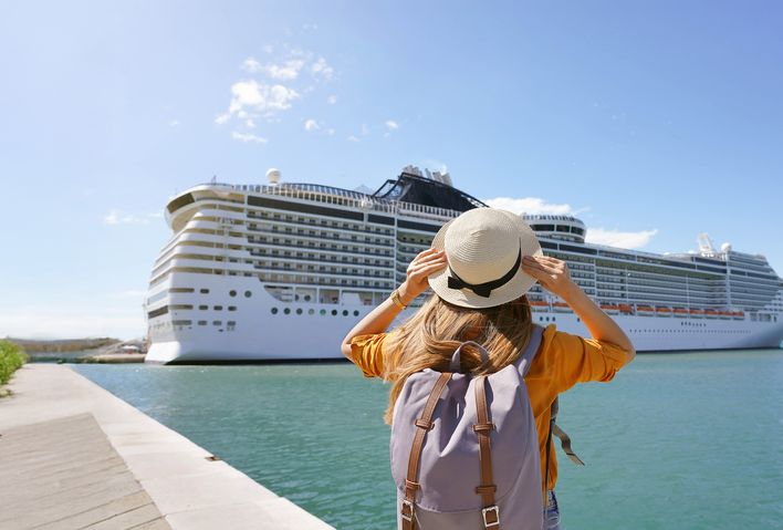 Frau steht vor einem Kreuzfahrtschiff an der Anlegestelle