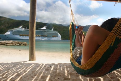 Frau am Strand vor Kreuzfahrtschiff