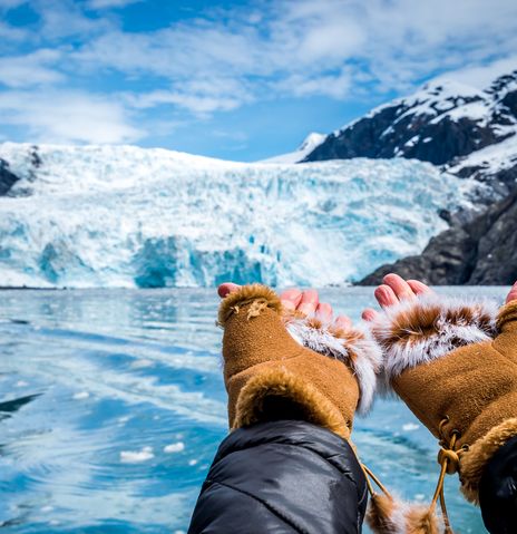 Hände zeigen auf eine Eiswand eines Gletschers mit blauem Eis in Alaska