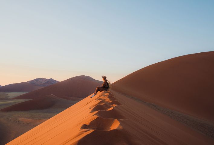 Frau sitzt in der Wüste im Namib Naukluft Nationalpark in Namibia und genießt den Ausblick