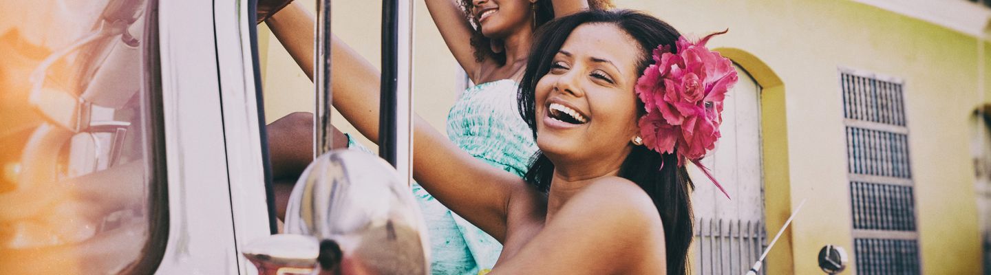 Lachende kubanische Frauen sitzen feiernd in einem Oldtimer