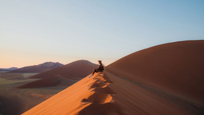 Frau sitzt in der Wüste im Namib Naukluft Nationalpark in Namibia und genießt den Ausblick