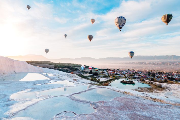 Weiße Kalkterrassen von Pamukkale mit Wasserbecken und Ballons am Himmel