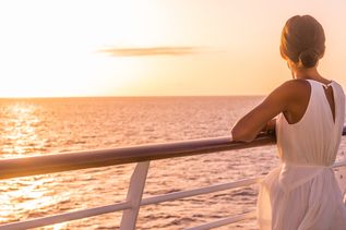 Frau bei Sonnenuntergang auf Kreuzfahrtschiff