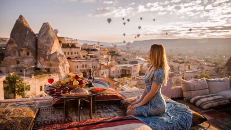 Frau mit Blick auf Felsenlandschaft und Heissluftballons