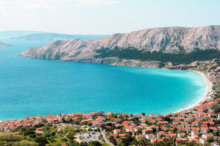 Luftaufnahme des Vela Plaža Strandes in Baška auf der Insel Krk, Kroatien, mit langem Kiesstrand und türkisfarbenem Meer