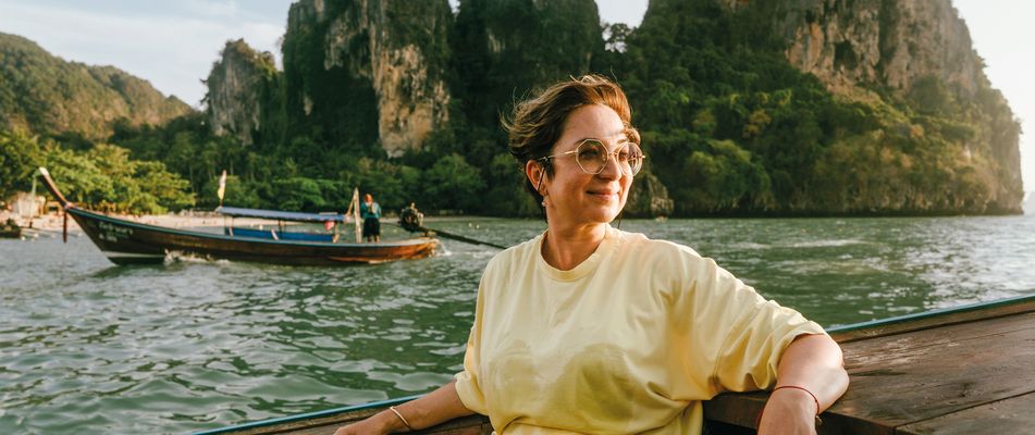 Frau genießt eine Bootsfahrt vor den Kalksteinfelsen der thailändischen Inselwelt bei Krabi