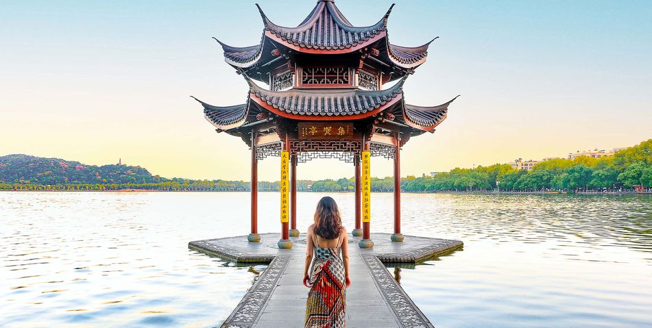 Frau in rotem Kleid vor traditionellem Pavillon am Westsee in Hangzhou