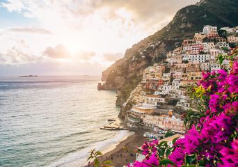 Panoramablick von der Küste Positanos in Italien über pinke Blumen auf Meer und Küstendörfer