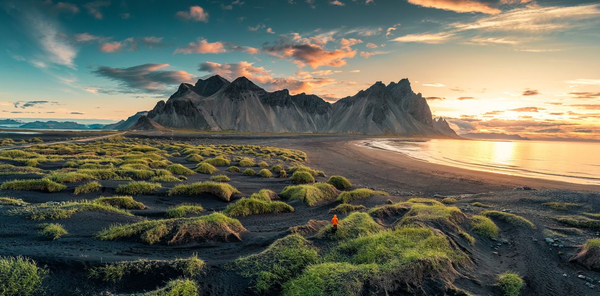 Mensch am schwarzen Strand Stokksnes mit Blick auf das Bergmassiv Vestrahorn in Island