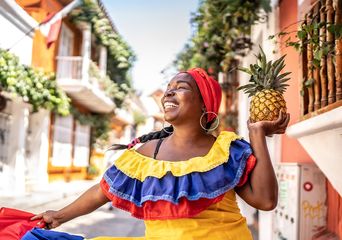 Eine fröhliche Frau in traditioneller kolumbianischer Tracht tanzt auf einer Straße in Cartagena