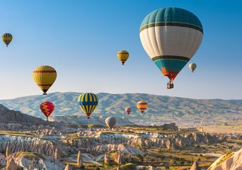 Heißluftballons steigen über Felsformationen in Kappadokien bei Sonnenaufgang