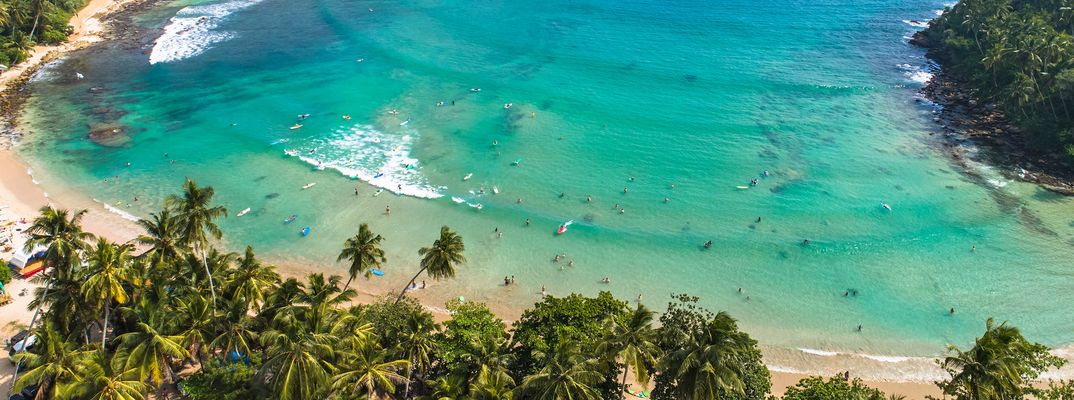 Luftaufnahme eines Surfstrands an der Südküste Sri Lankas mit türkisfarbenem Wasser und Palmen