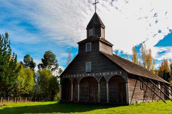 Holzkirche von Chiloé mit traditioneller Architektur und grünem Umfeld