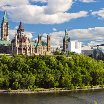 Blick auf Ottawa mit dem Parlamentsgebäude, Fluss und grüner Parklandschaft