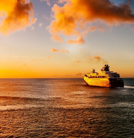 Kreuzfahrtschiff auf hoher See fahrend in den Sonnenuntergang