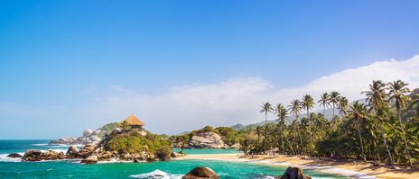 Karibikstrand in Tayrona-Nationalpark mit Felsen, Palmen und türkisfarbenem Meer