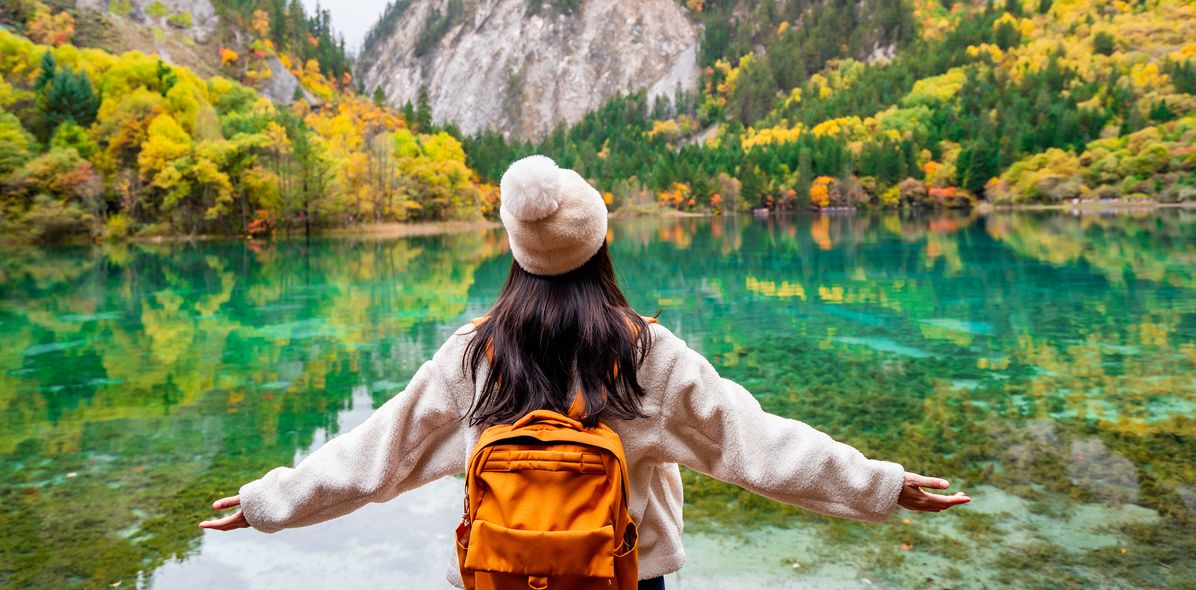 Frau schaut auf eine Herbstlandschaft im Jiuzhaigou-Nationalpark in Sichuan, China