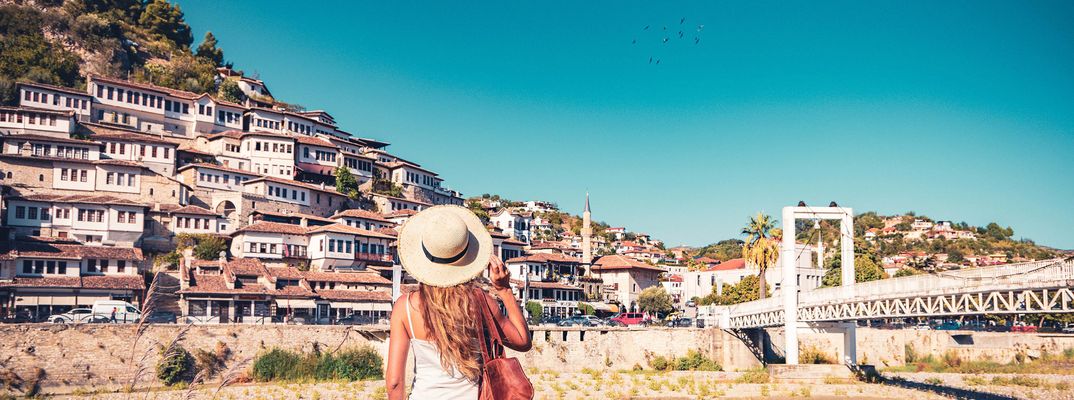 Frau mit einem Sonnenhut genießt den Ausblick auf die Stadt Berat in Albanien