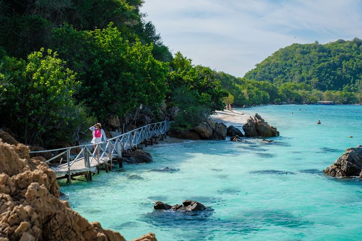 Eine Frau spaziert über die Brücke am Strand der Insel Koh Kham