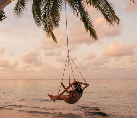 Frau auf Schaukel am Strand mit Palme